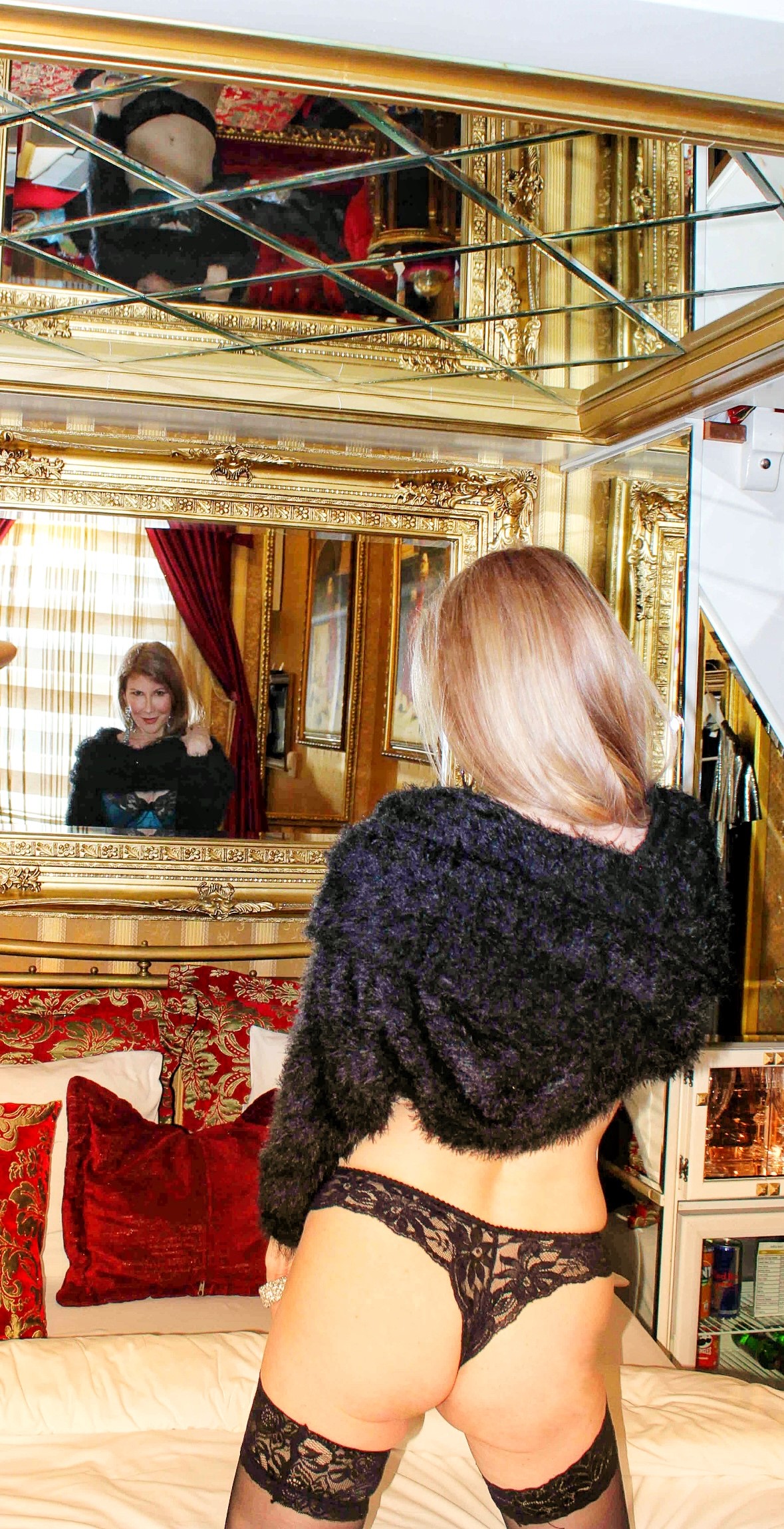 Francesca poses in front of a mirror in a lacy thong and faux fur stole